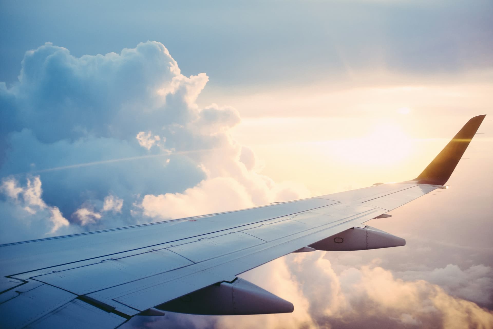 An airplane wing above the clouds at sunset.