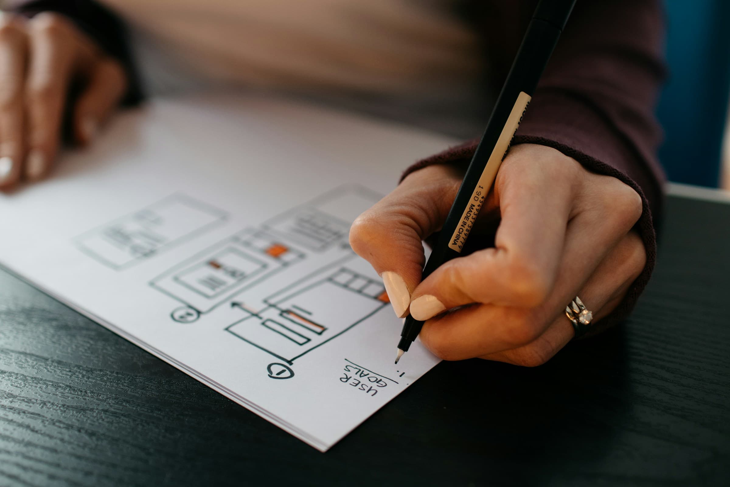 A designer sketching interface wireframes by hand.