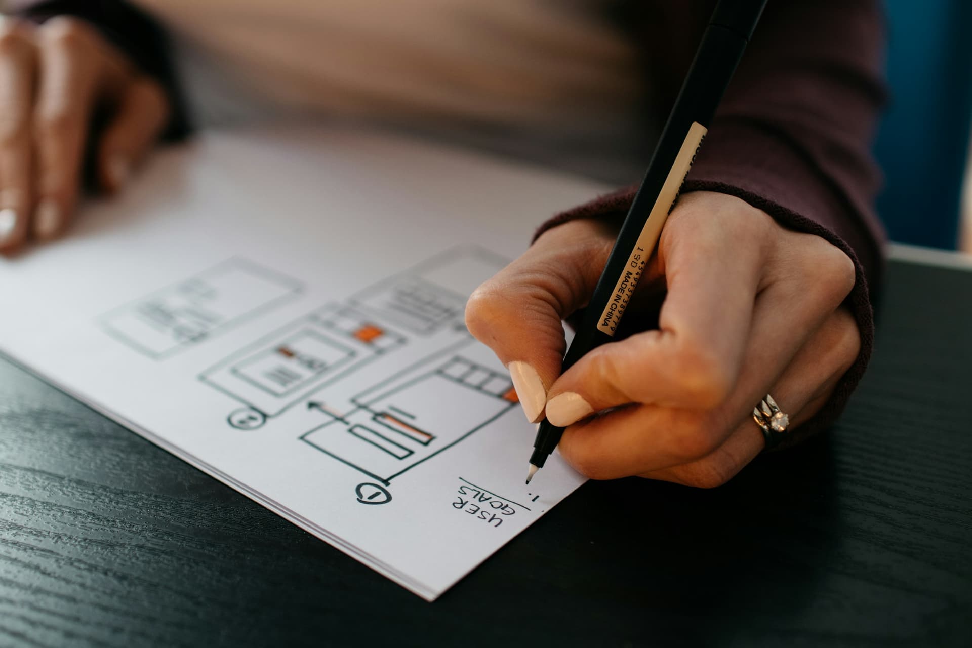 A designer sketching interface wireframes by hand.